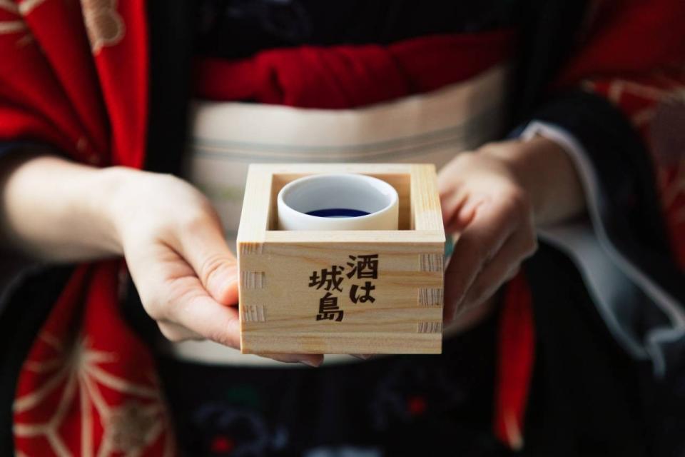 写真：桝に入った日本酒を持つ女性